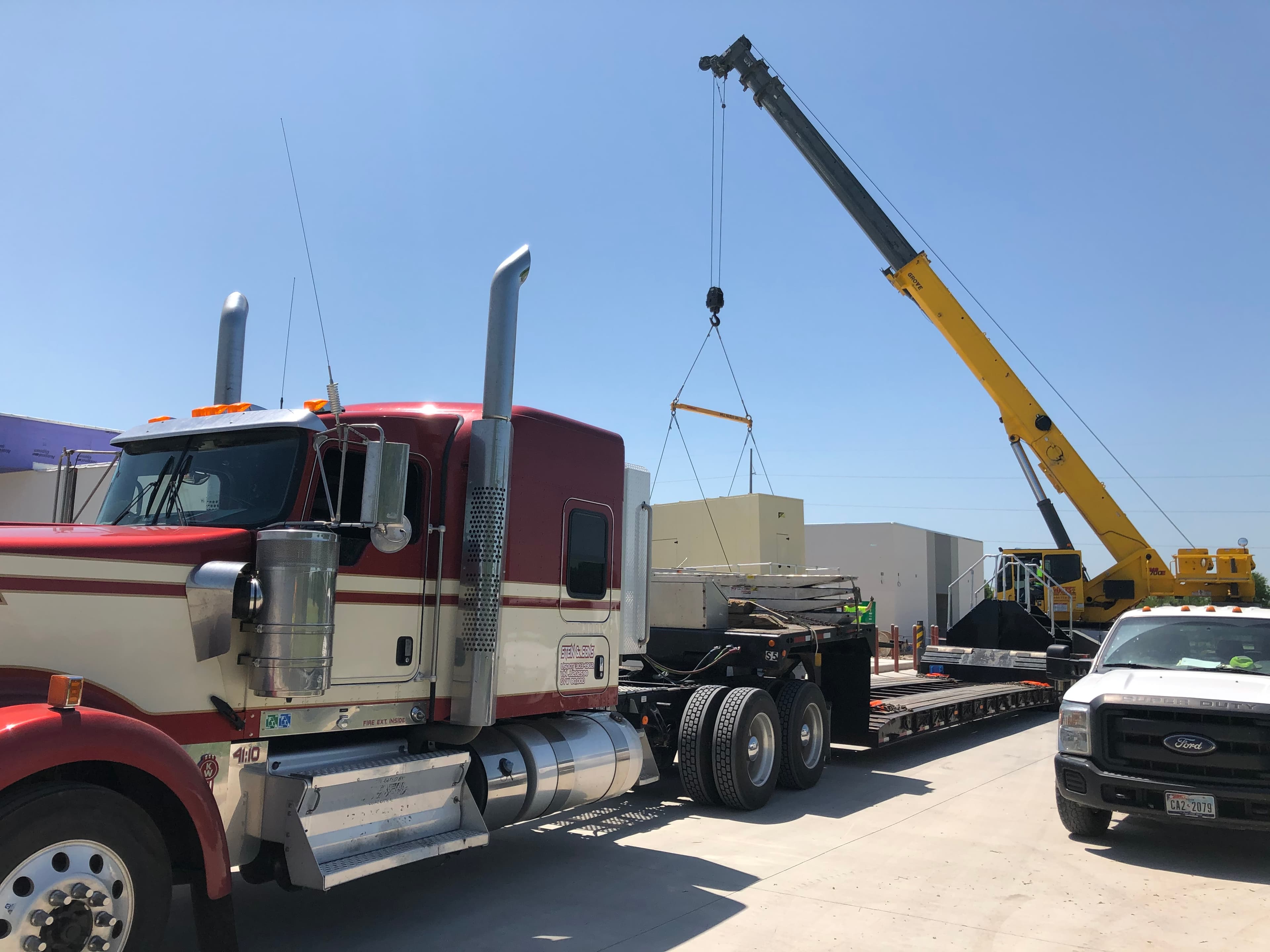Crane placing industrial freight onto a Stein & Sons RGN trailer