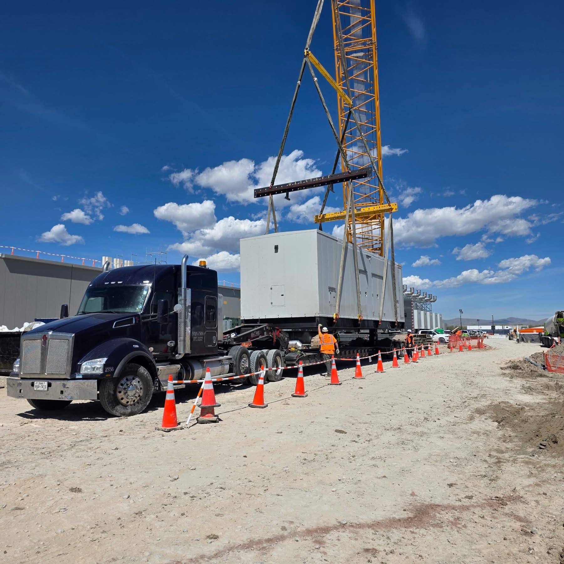 Crane placing modular unit on lowboy at industrial site